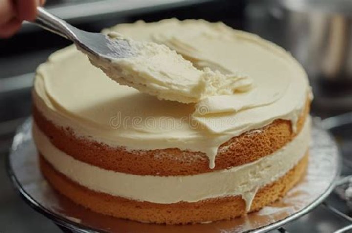 Frosting being spread on a square pumpkin cake.