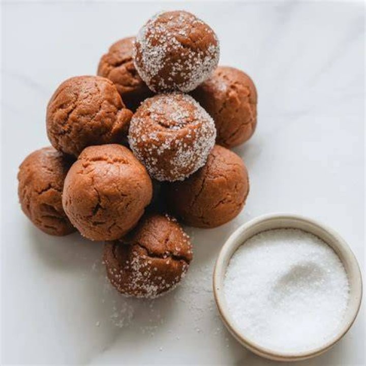 Ginger Molasses cookie dough balls in a bowl of sugar.